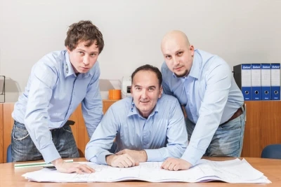 Trije svetovalci pri pregledu tehničnih načrtov za izbiro garažnih in industrijskih vrat